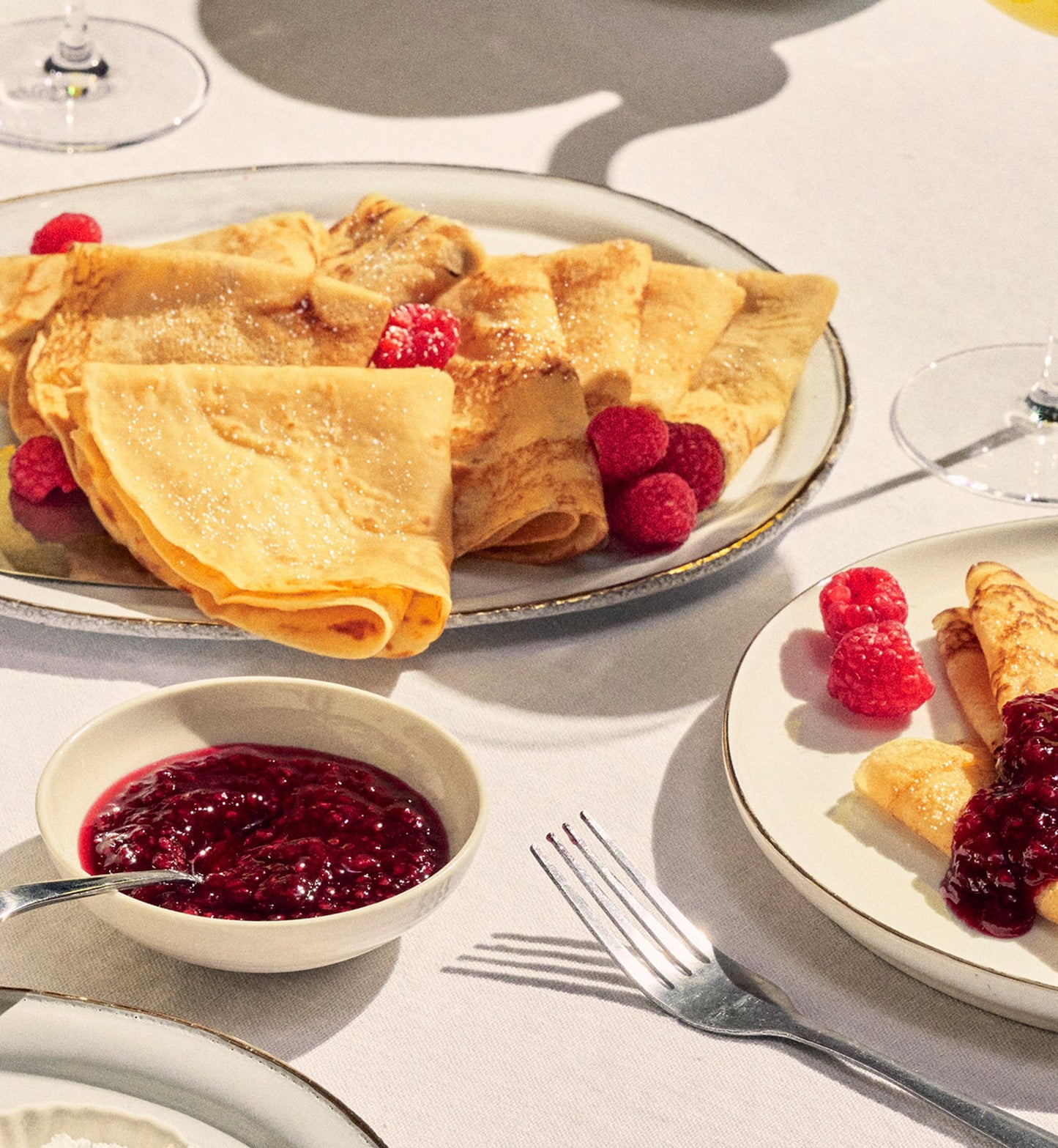 Crepes on a linen table with raspberry spread