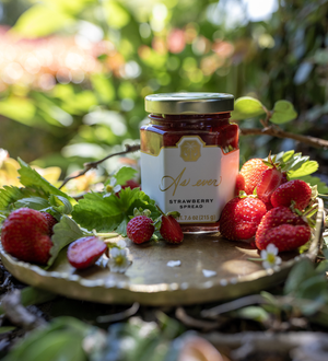 Jar of strawberry spread surrounded by fresh strawberries on a natural background