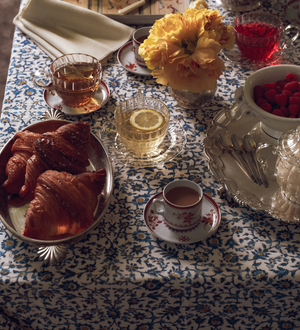 Table setting with tea, pastries, and flowers on a patterned tablecloth