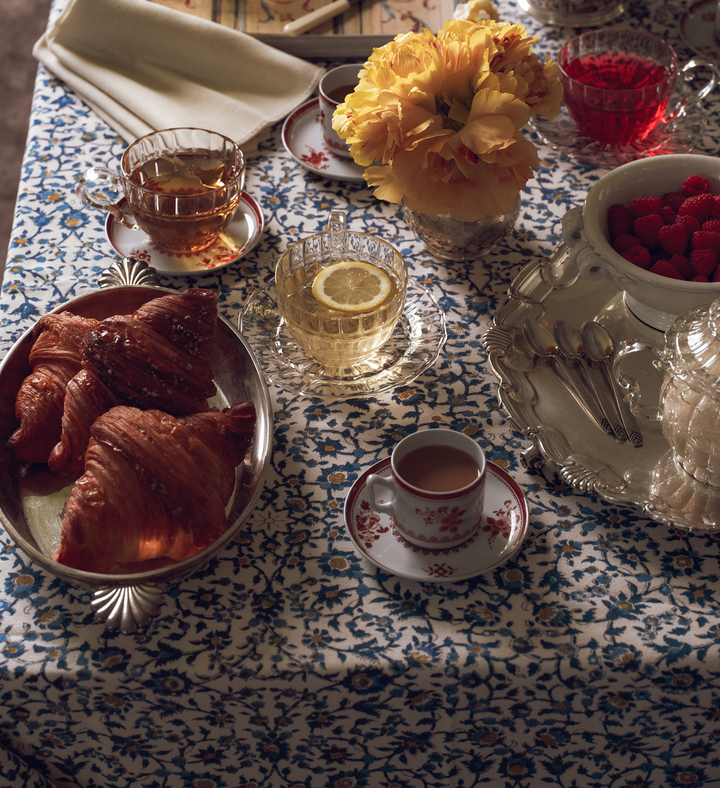 Table setting with tea, pastries, and flowers on a patterned tablecloth