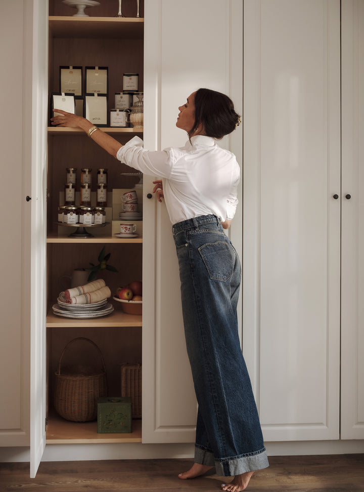 Woman reaching into a cabinet filled with kitchen items