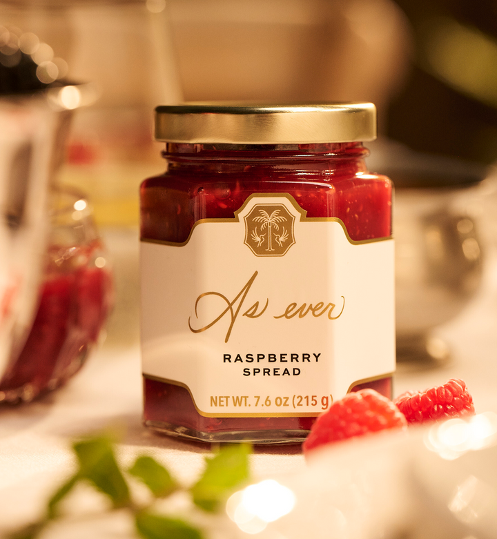Jar of raspberry spread with a decorative label on a blurred background