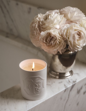 A candle sitting on the edge of a bath with a vase of flowers. 