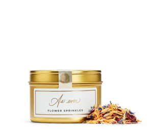 Gold tin of flower sprinkles with a decorative label, and loose flower sprinkles. 