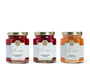 Three jars in a row, one with strawberry spread, one with raspberry spread, and one with orange marmalade. 