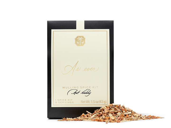 A black, beige, and gold package of mulling spice with loose spice in front of it. 