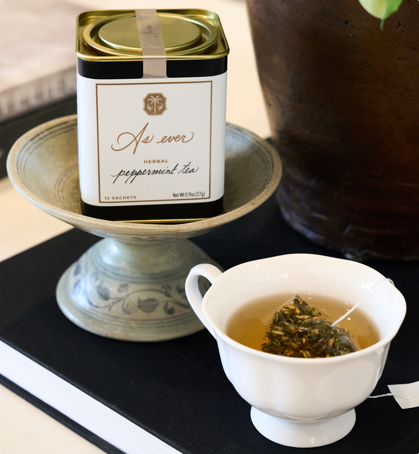 Tea canister labeled 'As ever' with a cup of tea on a black surface