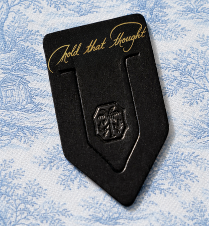 Black metal clip with 'Hold that Thought' text on a textured blue background