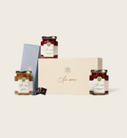 Three jars of strawberry jam with a decorative box on a light beige background