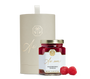 A jar of raspberry spread, raspberries, and a beige cylindrical box with gold detailing.
