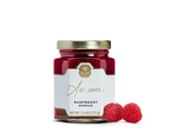 A jar of raspberry spread and two raspberries. 