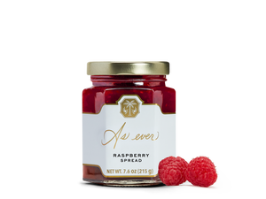 A jar of raspberry spread and two raspberries. 
