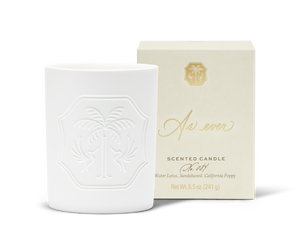 An unlit white candle with a decorative emblem beside a beige and gold candle box.