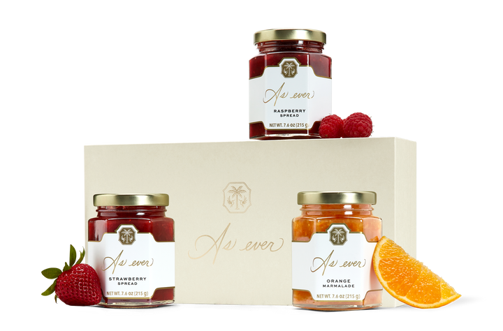 Three jars fruit spread, loose fruit, and a beige box with a gold logo.