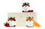 Three jars fruit spread, loose fruit, and a beige box with a gold logo.