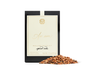 A black, beige, and gold package of mulling spice with loose spice in front of it. 