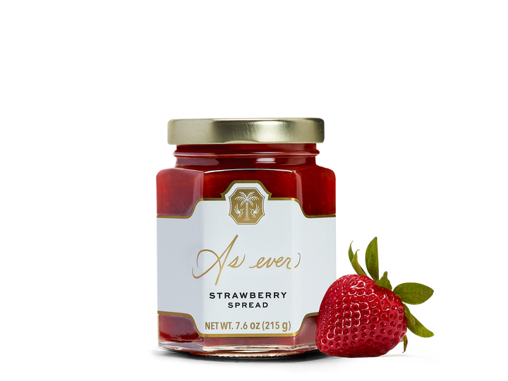 A jar of strawberry spread and a strawberry. 