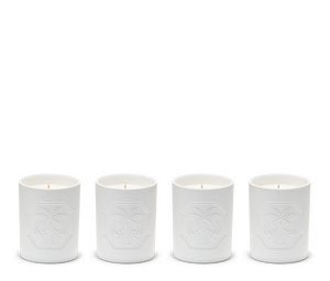 Four white candles in ceramic holders with embossed designs.