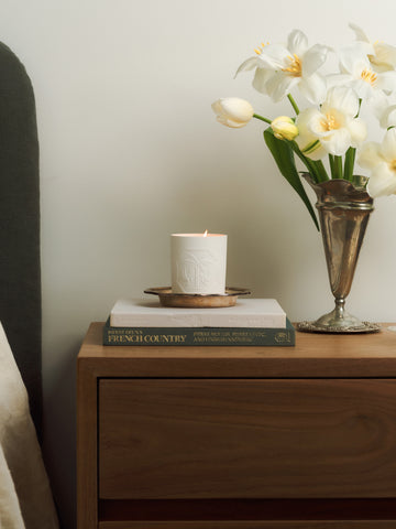 Candle and vase with flowers on a wooden bedside table. 